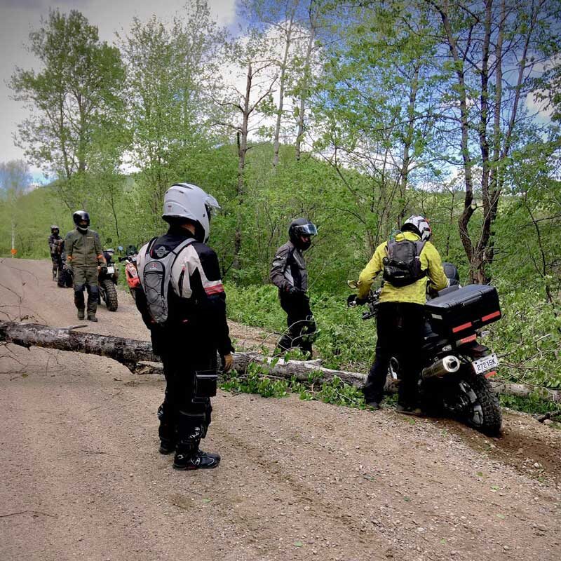 Group of adventure motorcyclists helping each other: group motorcycle touring is about having a built-in support system